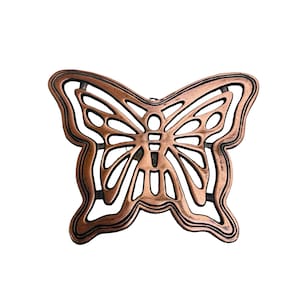 Peut inclure: Objet décoratif en forme de papillon avec un design ajouré. La pièce métallique a une finition cuivrée avec des accents noirs, créant un contraste. Les ailes et le corps du papillon sont clairement définis.