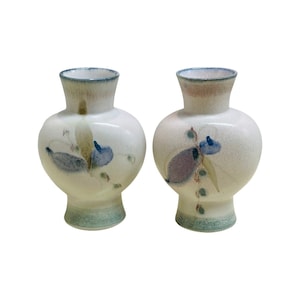 May include: Two white ceramic vases with floral designs. The vases have a light blue, purple, and green floral pattern.