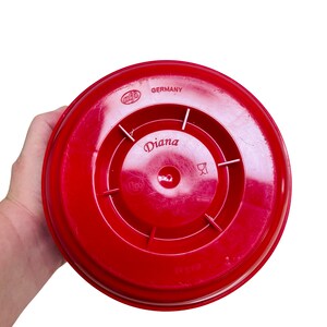 May include: Red plastic lid with a circular design and the text "Diana" in the center. The lid also has the text "Germany" and "Glass Nr. 2712" printed on it.