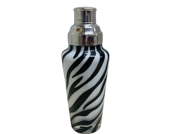 May include: A black and white zebra patterned cocktail shaker with a silver top.