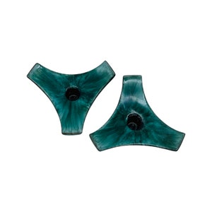May include: A pair of teal green ceramic candle holders with a triangular shape and a circular hole in the centre for a candle.