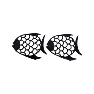 May include: A set of two black cast iron fish-shaped hot pads. The fish have a detailed design of scales and a simple eye.