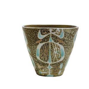 May include: A brown ceramic planter with a geometric design in white and blue. The planter has a textured surface and a wide, rounded base.