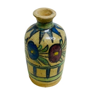 Puede incluir: Un pequeño jarrón de cerámica pintado a mano con un diseño floral amarillo, azul, verde y rojo. El jarrón tiene un cuerpo redondeado y un cuello estrecho.