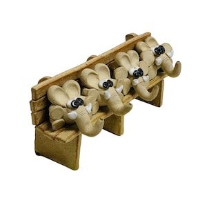 Peut inclure: Un banc en céramique avec quatre figurines d'éléphants. Les éléphants sont de couleur beige clair avec des yeux noirs et des défenses blanches. Le banc est de couleur marron clair.