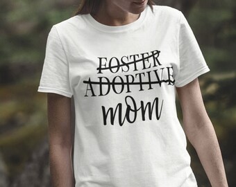 May include: White t-shirt with black text that reads "Foster Adoptive Mom" with the word "Adoptive" crossed out.