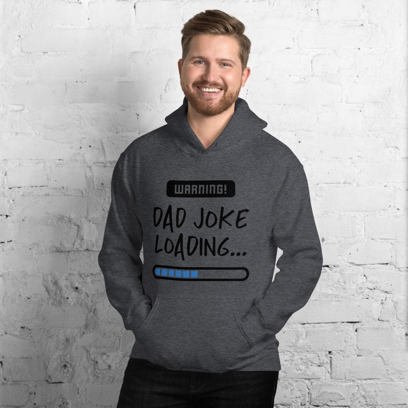 May include: Dark gray hoodie with the text "WARNING! DAD JOKE LOADING..." in black. The hoodie has a drawstring hood and a front pocket. The text is above a blue progress bar.