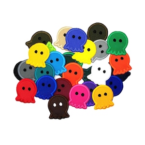 May include: A collection of colorful felt ghost-shaped buttons with various facial expressions. The buttons are in a variety of colors, including red, blue, green, yellow, orange, purple, and black.