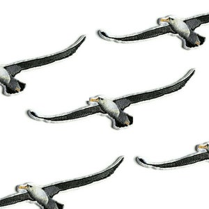 Op de afbeelding: Vijf gestikte strijkbare patches van albatrossen in vlucht, in zwart en wit.