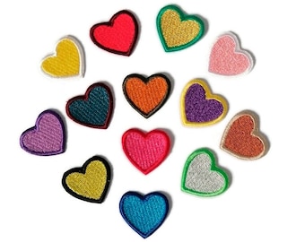 May include: Assortment of 12 colorful heart-shaped iron-on patches. The patches are in various colors, including red, orange, yellow, green, blue, purple, pink, and brown.