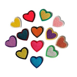 Könnte beinhalten: Sortiment von 12 bunten herzförmigen Bügelbildern. Die Patches sind in verschiedenen Farben, darunter Rot, Orange, Gelb, Grün, Blau, Lila, Rosa und Braun.