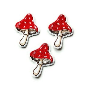 Puede incluir: Tres parches bordados de setas rojas y blancas. Las setas tienen puntos blancos y un tallo blanco.