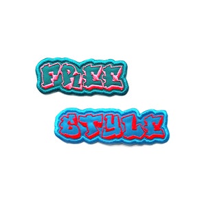 May include: Two embroidered patches with a blue outline and pink lettering. The top patch says "FREE" and the bottom patch says "STYLE".