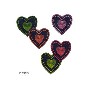 Puede incluir: Parches bordados con forma de corazón en varios colores neón: verde, naranja, rosa y rojo, sobre un fondo azul oscuro. La palabra "neon" está impresa en blanco.