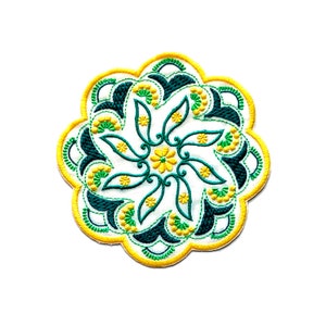 May include: A circular embroidered patch with a green, yellow, and white floral design. The design features a central flower with swirling leaves and petals.