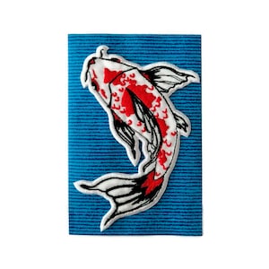 Puede incluir: Un parche bordado de pez koi blanco y rojo sobre un fondo azul. El pez nada hacia la derecha con su aleta caudal extendida.