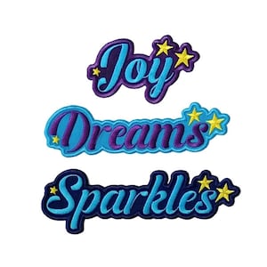 Könnte beinhalten: Drei gestickte Aufnäher mit den Worten "Joy", "Dreams" und "Sparkles" in blauer und violetter Schrift mit gelben Sternen.