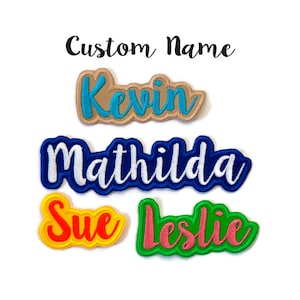 May include: Four embroidered iron-on patches with different names: Kevin in blue on tan, Matilda in white on blue, Sue in orange on yellow, and Leslie in pink on green.