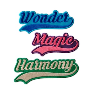 May include: Three embroidered patches with the words "Wonder", "Magic", and "Harmony" in a retro style font. The patches are in blue, pink, and green.