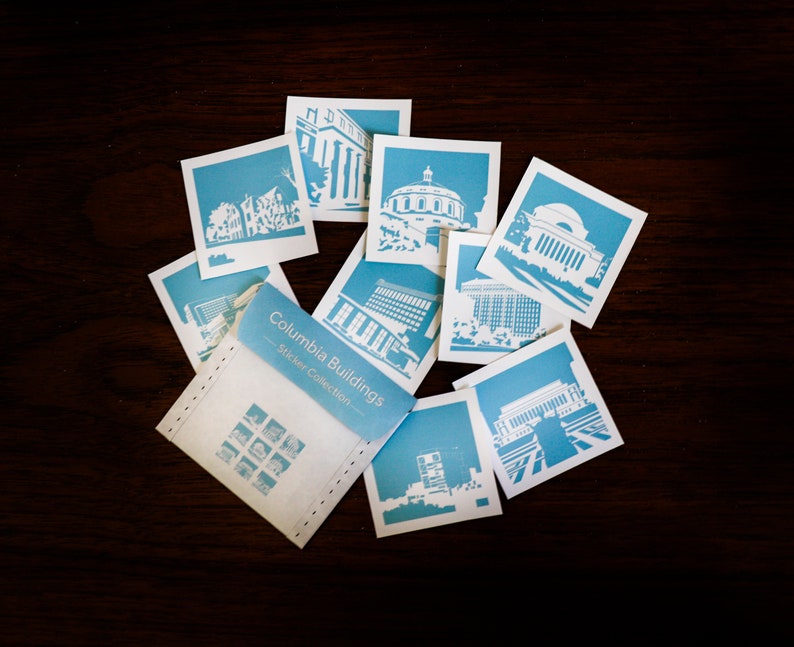 Puede incluir: Un conjunto de pegatinas azules y blancas con diferentes edificios del campus de la Universidad de Columbia. Las pegatinas est&aacute;n empaquetadas en un sobre blanco con el texto "Columbia Buildings Sticker Collection".