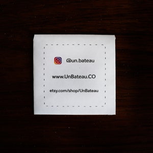 Puede incluir: Una tarjeta blanca con un borde negro discontinuo. La tarjeta tiene un icono de redes sociales, el texto "@un.bateau", el sitio web "www.UnBateau.CO" y el enlace de la tienda Etsy "etsy.com/shop/UnBateau".