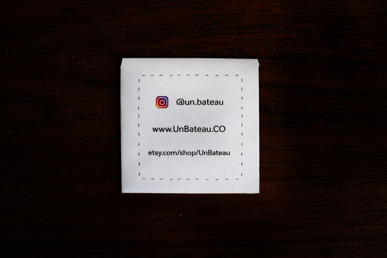 Puede incluir: Una tarjeta blanca con un borde negro discontinuo. La tarjeta tiene un icono de redes sociales, el texto "@un.bateau", el sitio web "www.UnBateau.CO" y el enlace de la tienda Etsy "etsy.com/shop/UnBateau".