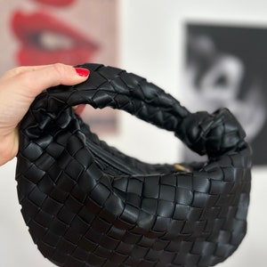 Introducing our stylish and versatile black vegan leather zipper pouch, featuring a unique woven knot design. use it as a makeup bag, clutch. Handcrafted with high-quality vegan leather, this pouch is both cruelty-free and eco-friendly. bottega jodie