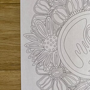 K&ouml;nnte beinhalten: Eine Schwarzwei&szlig;-Zeichnung eines Mandalas mit floralem Design. Das Mandala besteht aus mehreren sich &uuml;berlappenden Blumen mit filigranen Details.
