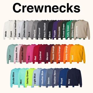 Puede incluir: Una variedad de sudaderas de cuello redondo en varios colores, incluyendo blanco, negro, morado y dorado. La palabra "Crewnecks" se muestra en letras negras grandes y en negrita en la parte superior de la imagen. Cada sudadera se muestra con su nombre de color.