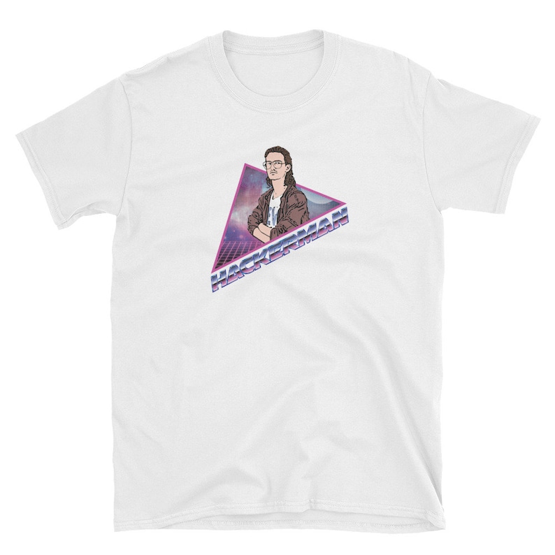 May include: White t-shirt with a retro-style graphic of a person wearing glasses and a brown jacket. The graphic is in a triangle with the text "HACKERMAN" in a purple and blue gradient.