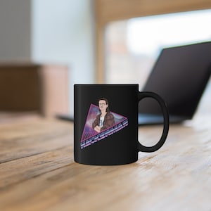 Könnte beinhalten: Schwarze Keramik-Kaffeetasse mit einer Retro-Grafik einer Person mit einem Pferdeschwanz und dem Text "Hackerman".