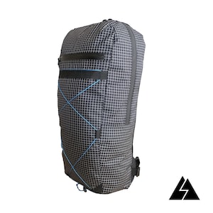 Puede incluir: Una mochila negra y azul con un patrón de cuadrícula y un bolsillo con cremallera. La mochila tiene un cordón azul en la parte inferior.
