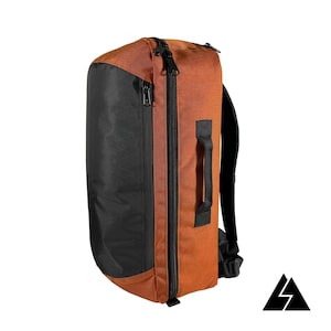 Może przedstawiać: Brązowo-czarny plecak podróżny z kieszenią z przodu na zamek błyskawiczny i uchwytem po boku.