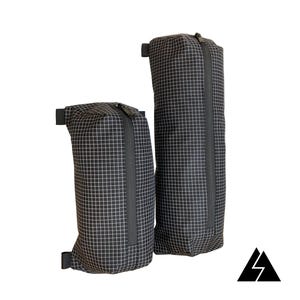 May include: Two black zippered pouches with a grid pattern. The pouches are hanging from a wall and are different sizes.
