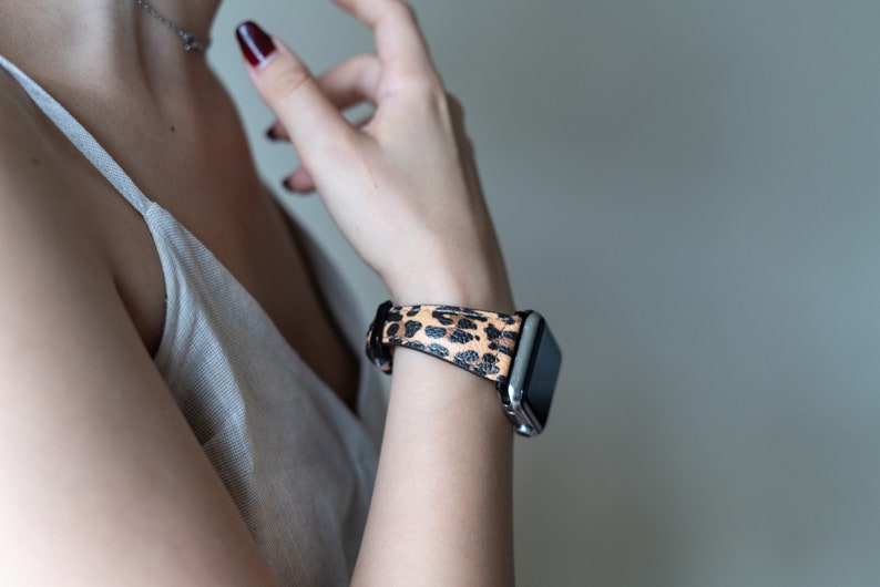 May include: A silver smartwatch with a black and brown leopard print band.