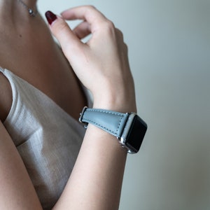May include: A gray leather watch band with a silver watch face.