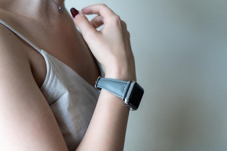 May include: A gray leather watch band with a silver watch face.