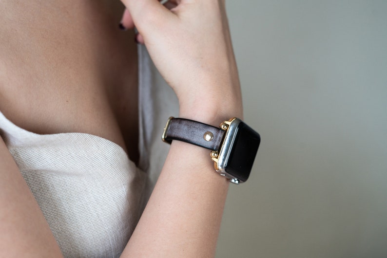 Op de afbeelding: Een bruin leren horlogebandje met gouden accenten op een zilveren smartwatch.