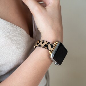 May include: A silver and gold Apple Watch with a black screen and a leopard print band.