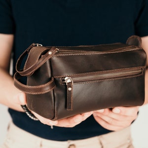 May include: A brown leather travel bag with a zip closure and a handle.