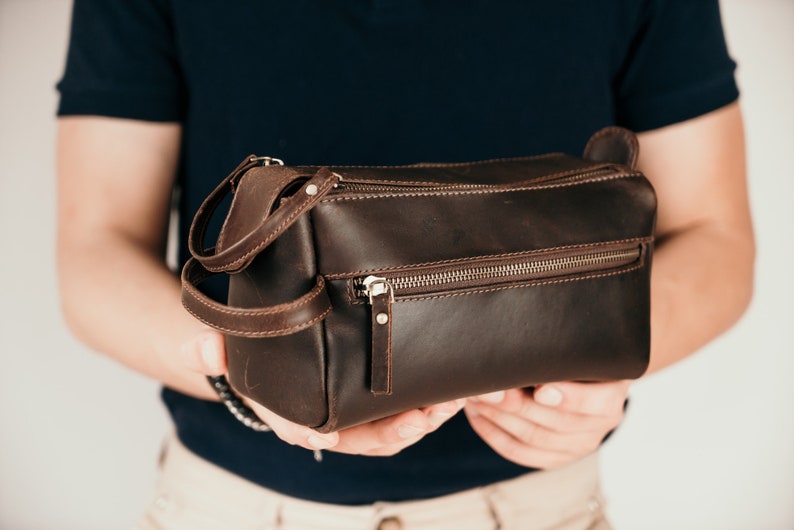 May include: A brown leather travel bag with a zip closure and a handle.