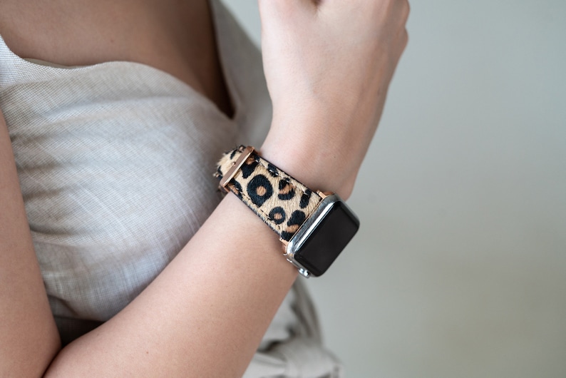 May include: A black smartwatch with a leopard print band. The band is made of brown and black faux fur.