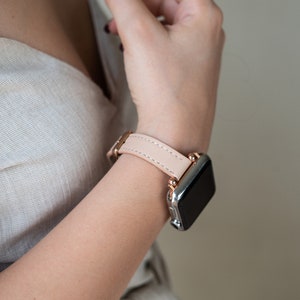 May include: A light pink leather watch band with a rose gold buckle and a silver smartwatch.