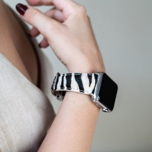 May include: A silver smartwatch with a black and white zebra print band.