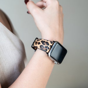 May include: A black smartwatch with a leopard print band. The watch face is black and the band is brown and black.