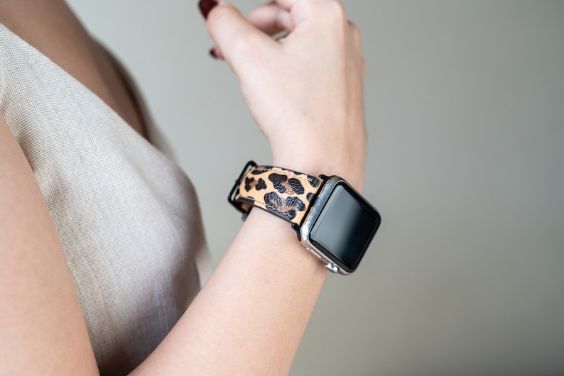 May include: A black smartwatch with a leopard print band. The watch face is black and the band is brown and black.