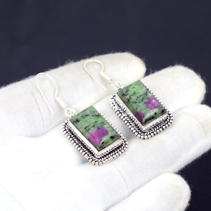 Puede incluir: Pendientes de plata con piedras rectangulares de rubí zoisita. Las piedras son verdes con toques rosas, engastadas en un marco plateado con un borde de cuentas. Cierre de gancho.