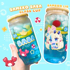 Pode incluir: Três copos de vidro com tampas de bambu, cheios de líquido azul e elementos decorativos. Cada copo apresenta um desenho de personagem de desenho animado e o texto "SAMEKO SABA GLASS CUP". Os copos têm 473 ml.