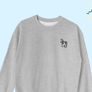 May include: A gray sweatshirt with a small black and white zebra graphic on the left chest.