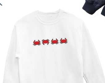 May include: White long-sleeved sweatshirt with four red crabs embroidered on the front.